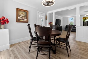 A dining area with a wooden table and chairs, a painting on the wall, and a door leading to another room. - A 5 minute walk to the country park beach (Brooklyn)