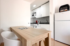 Une cuisine moderne avec des meubles blancs, un four à micro-ondes, un lave-linge et un réfrigérateur.