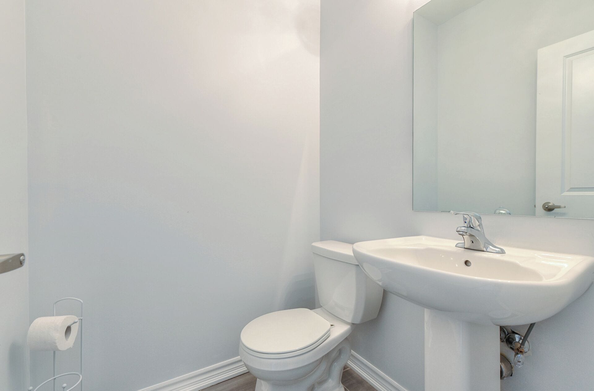 A bathroom with a toilet, sink, and mirror.