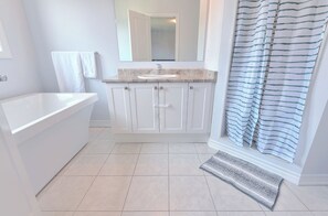 Ein Badezimmer mit Badewanne, Waschbecken, Spiegel und Duschvorhang.