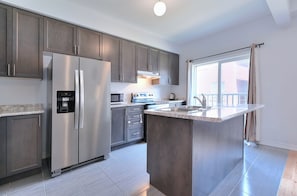 A modern kitchen with stainless steel appliances, a built-in oven, and a large window.