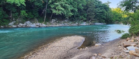 Une rivière aux eaux claires, bordée de rochers et d’arbres.