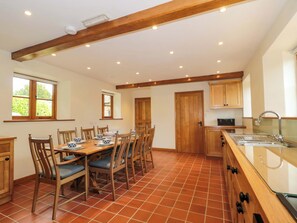 Ein Essbereich mit Holztisch und -stühlen, eine Küche mit Holzausbau und ein Fliesenboden.
