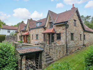 Ein Steinhaus mit geneigtem Dach, einer Veranda und einem kleinen Garten.