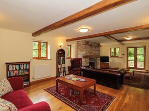 Ein gemütliches Wohnzimmer mit Kamin, Bücherregalen, einem roten Sofa und einem Holztisch.