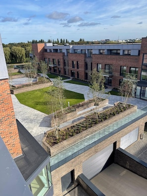 A modern building with a rooftop garden, brick walls, and a glass walkway. - One Double Room in the Apartament (Peterborough)