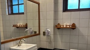 A bathroom with a white sink, a toilet, a mirror, and a window. - Hotel Boutique Wenupillan (Villarrica)