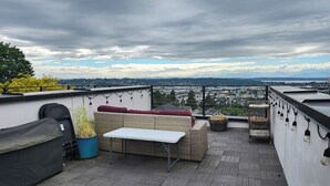 A rooftop terrace with a sofa, table, and potted plants. - Phinney Ridge Comfy Digs! (Seattle)