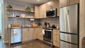 A modern kitchen with wooden cabinets, stainless steel appliances, a microwave, and a built-in oven. - Phinney Ridge Comfy Digs! (Seattle)