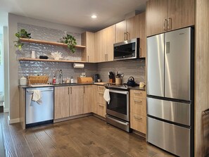 A modern kitchen with wooden cabinets, stainless steel appliances, a microwave, and a built-in oven. - Phinney Ridge Comfy Digs! (Seattle)