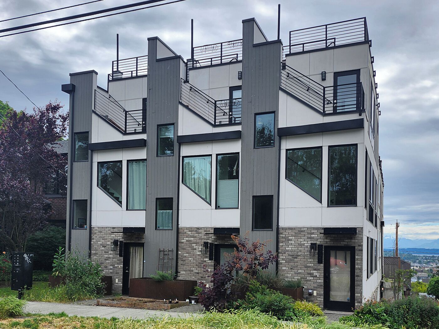 A modern multi-story building with a mix of brick and white exterior, large windows, and a visible staircase. - Phinney Ridge Comfy Digs! (Seattle)