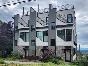Um edifício moderno de vários andares com fachada em tijolo e branco, grandes janelas e uma escadaria visível.