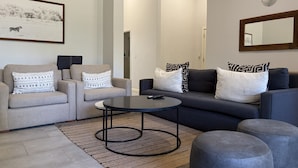 A modern living room with a sofa, armchairs, a coffee table, and a rug. - Luxury 2-bedroom apartment in Victoria Falls near the falls (Victoria Falls)
