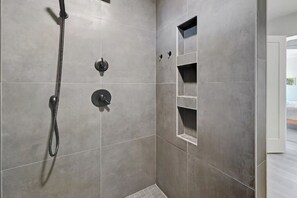 A shower with a handheld showerhead, a wall-mounted control, and a shelf unit. - Expansive Marfa Views: 3-Bedroom, 2-Bath Home with spacious patios and views (Marfa)