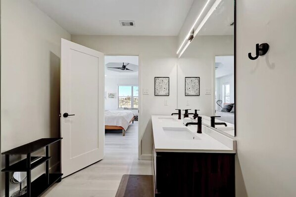 A modern bathroom with a large mirror, two sinks, and a ceiling fan.