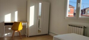 A room with a bed, a desk with a chair, a wardrobe, and a window. - Vrbo Property (Cangas)