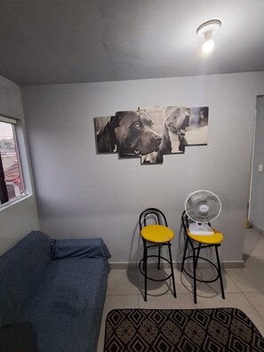 A room with a grey sofa, a wall-mounted dog photo collage, two chairs with a fan, and a patterned rug. - Vrbo Property (São Paulo)