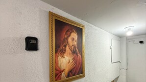 Un pasillo con un cuadro enmarcado en la pared, un detector de humo y una puerta.