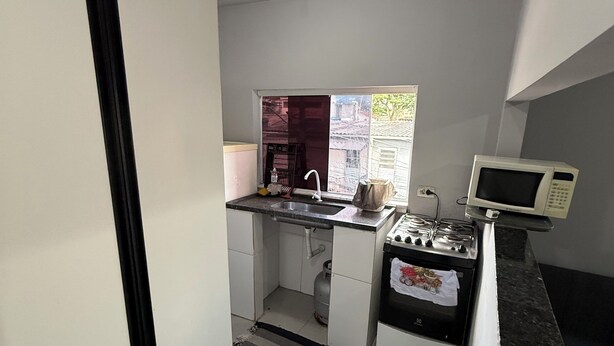 Una cocina compacta con estufa a gas, microondas y fregadero.