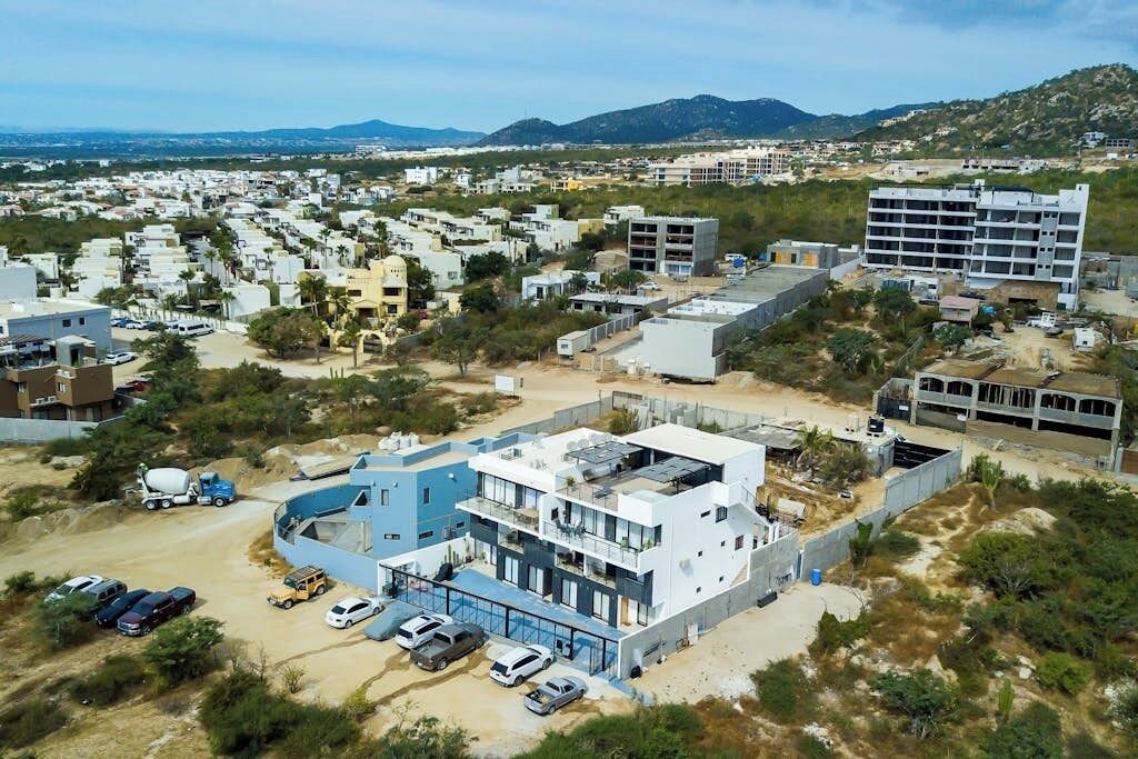 A modern building with a blue and white color scheme, surrounded by a parking area and other residential buildings.