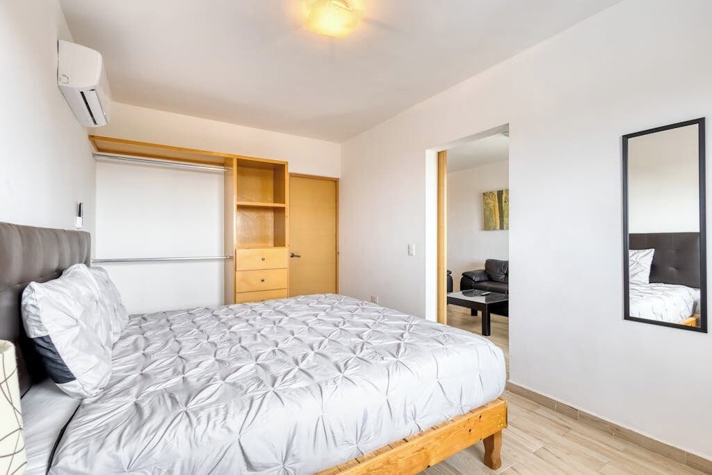 Quarto com cama, guarda-roupa, escrivaninha e espelho.