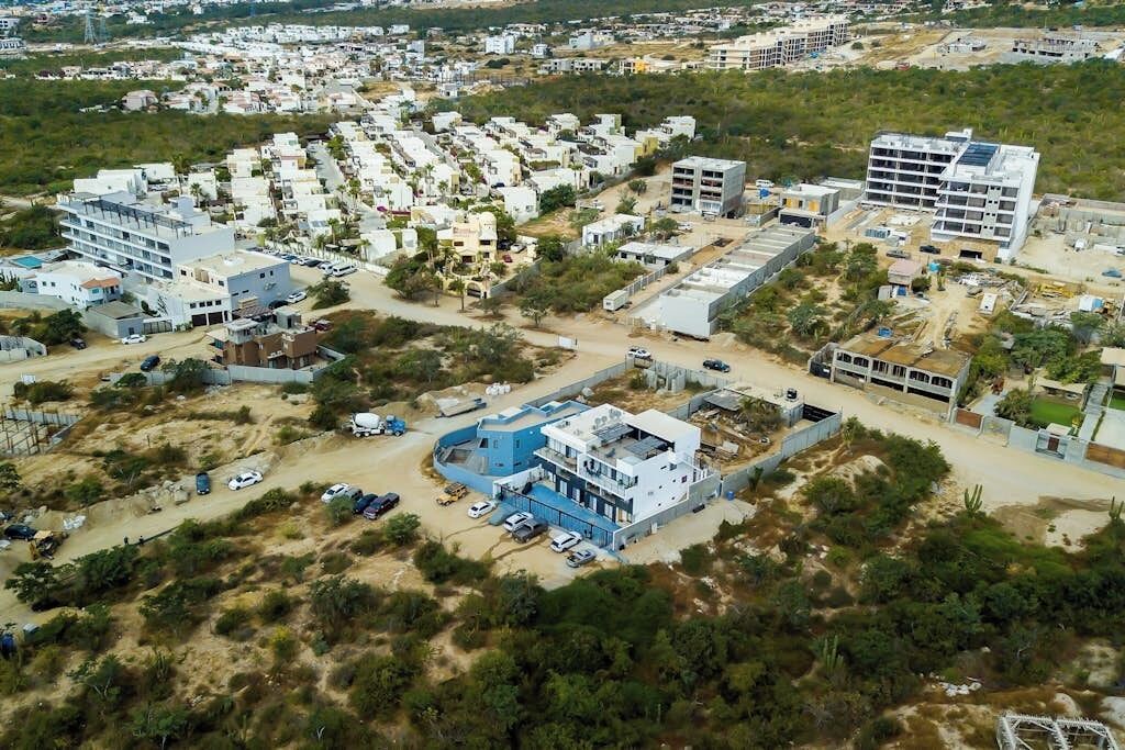 An aerial view of a residential area with multiple buildings, including a prominent blue structure with a curved roof.