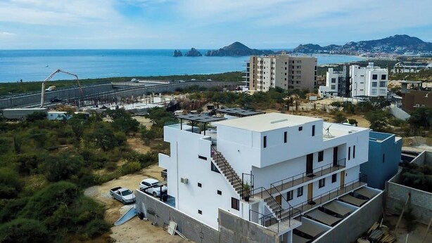 Un edificio moderno con tejado plano, una escalera y vistas al mar y las montañas.