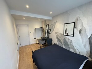 Quarto com cama, escrivaninha, cadeira, guarda-roupa e espelho.