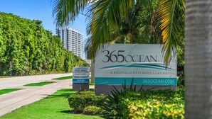 Señal de 365ocean, un hotel boutique para estancias prolongadas, con dirección web y números de contacto.