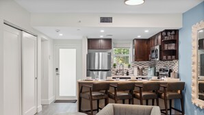 Una cocina moderna con una isla central, taburetes de bar y una mesa de comedor.
