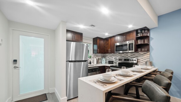 Una cocina moderna con una isla central, electrodomésticos de acero inoxidable y armarios de madera oscura.
