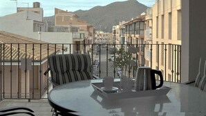 A balcony with a table, chairs, and a view of a street and mountains. - Roger de Flor in Puerto Pollensa (Pollença)