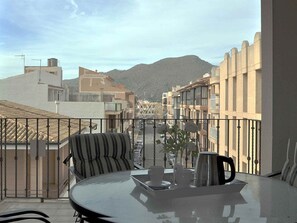 A balcony with a table, chairs, and a view of a street and mountains. - Roger de Flor in Puerto Pollensa (Pollença)