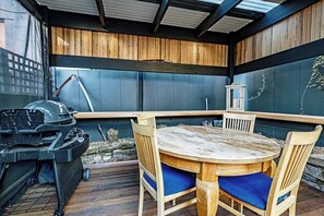 An outdoor patio with a round wooden table and chairs, a grill, and a lantern. - Bobs Cottage Nostalgic Charm and Homely Comfort (Dynnyrne)