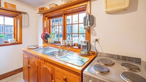 Una cucina con mobili in legno, un lavello, un fornello e una finestra con persiane.