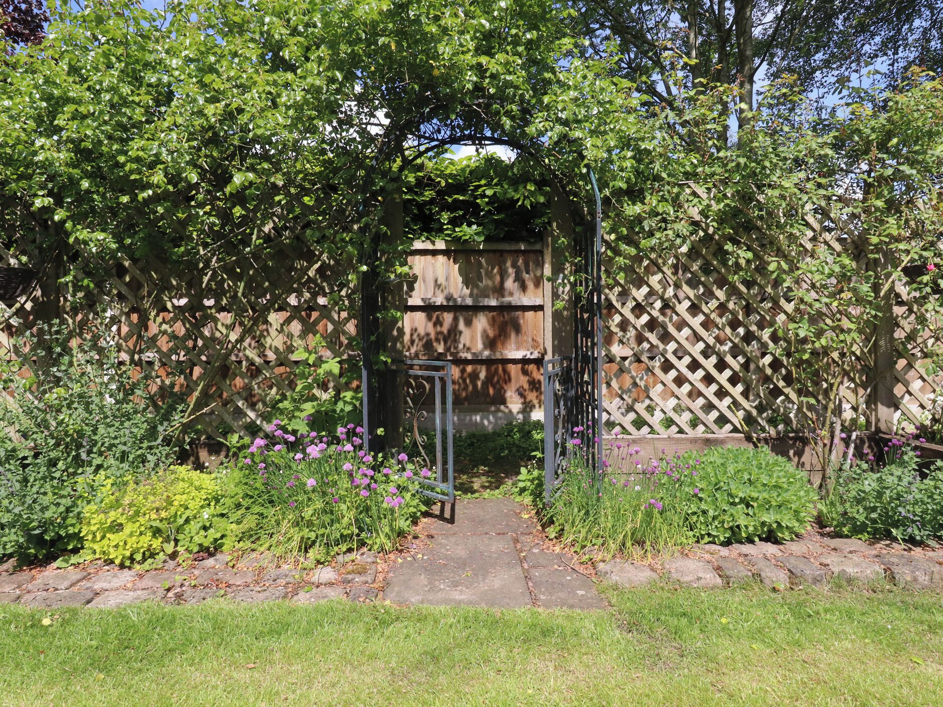 A garden with a wooden fence, a metal gate, and various plants.