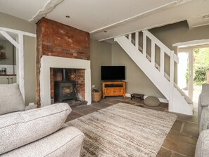 Ein Wohnzimmer mit Kamin, Treppe, Fernseher und einer Couch.