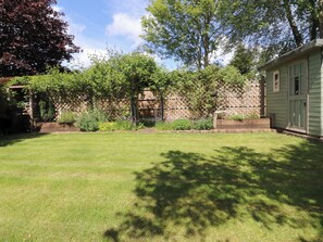 Ein gepflegter Garten mit Rasen, Holzzaun und einem Gebäude mit einer Tür.