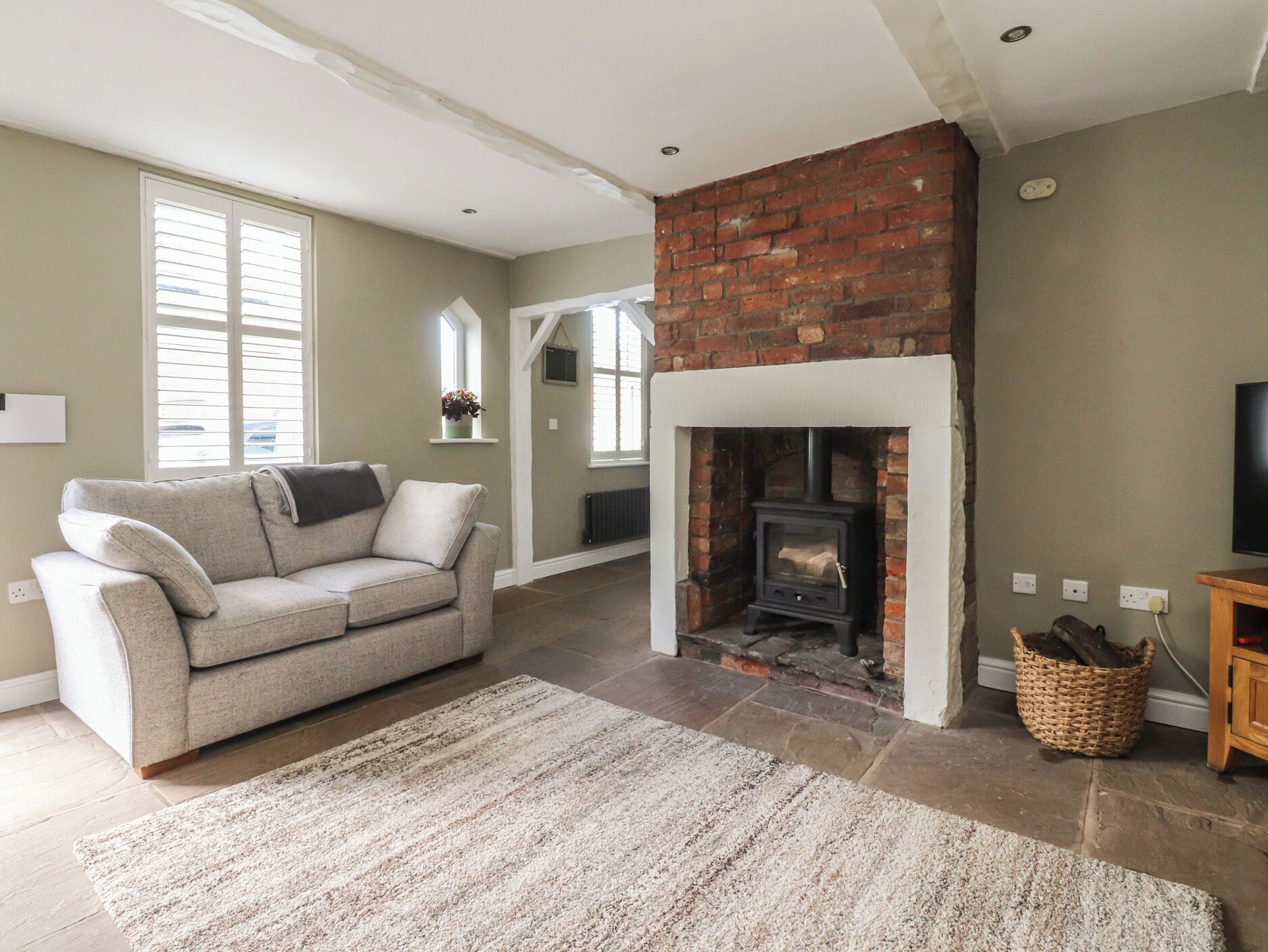 A living room with a fireplace, a sofa, a rug, and a brick wall.