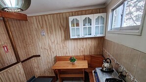 Cuina compacta amb taula de fusta, microones, bullidor, rentapelats i una finestra.