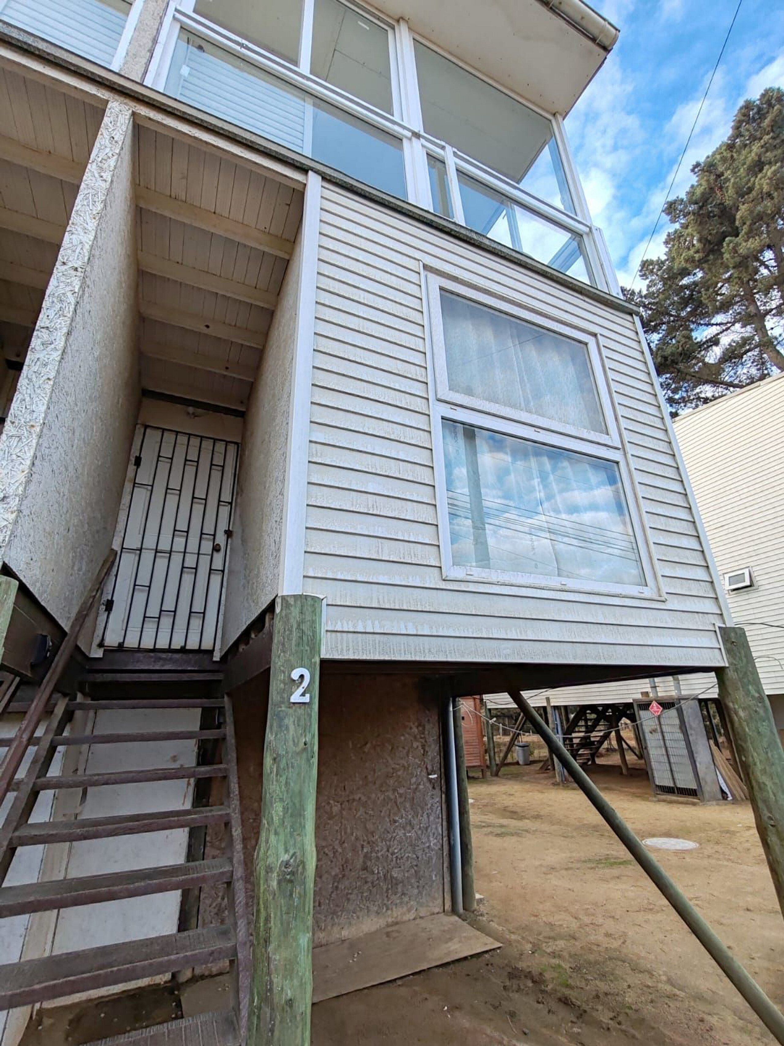 A two-story building with a visible number '2' on the front, a set of stairs leading to the entrance, and a large window on the upper floor.