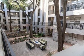 Un patio de varios niveles con mesas al aire libre, árboles y luces colgantes.