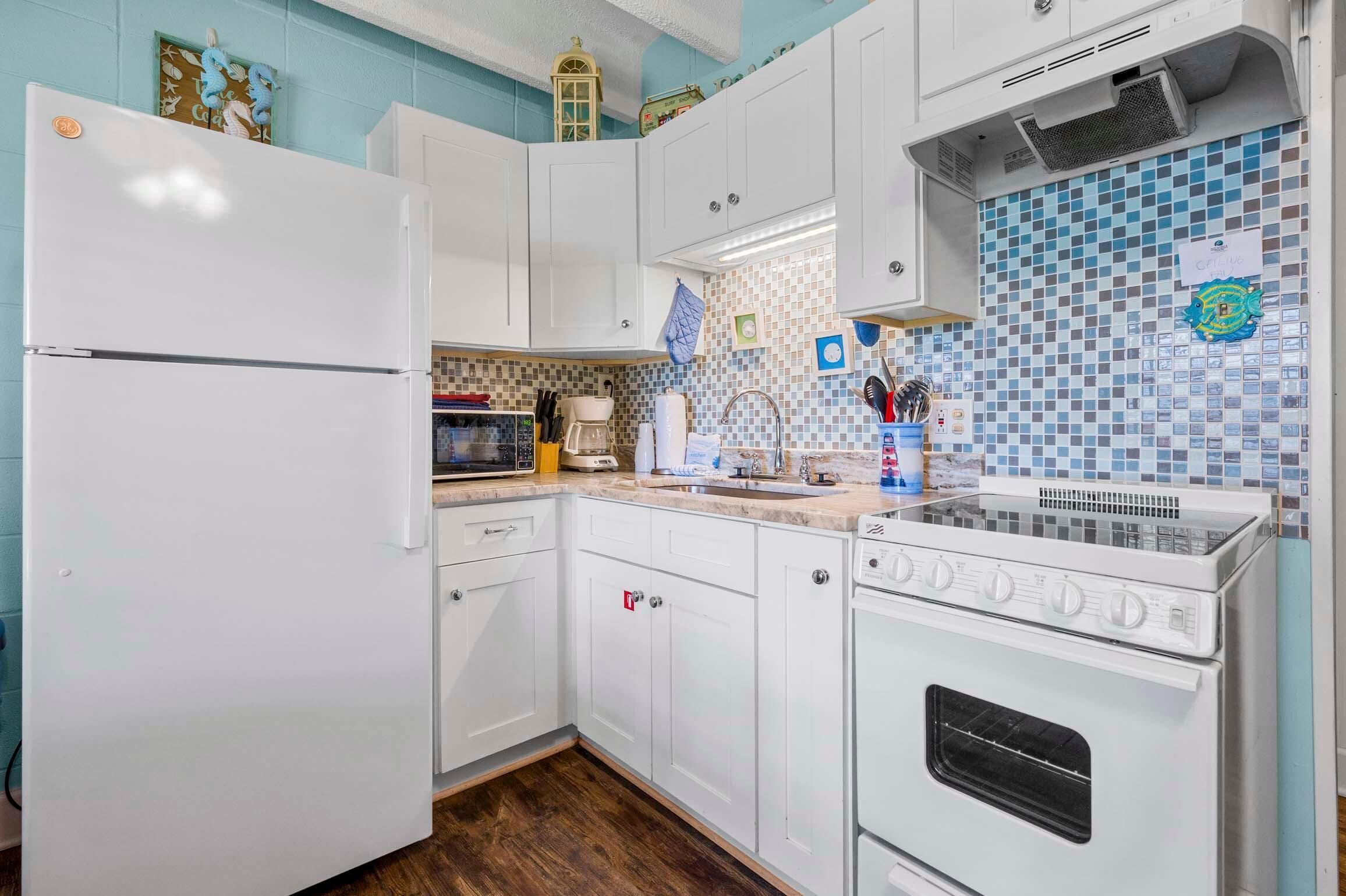 A kitchen with white cabinets, a microwave, a coffee maker, and a stove.