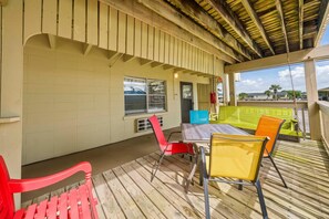 A covered outdoor area with a table and chairs, a window, and a door. - Gulf Village 101 (Gulf Shores)