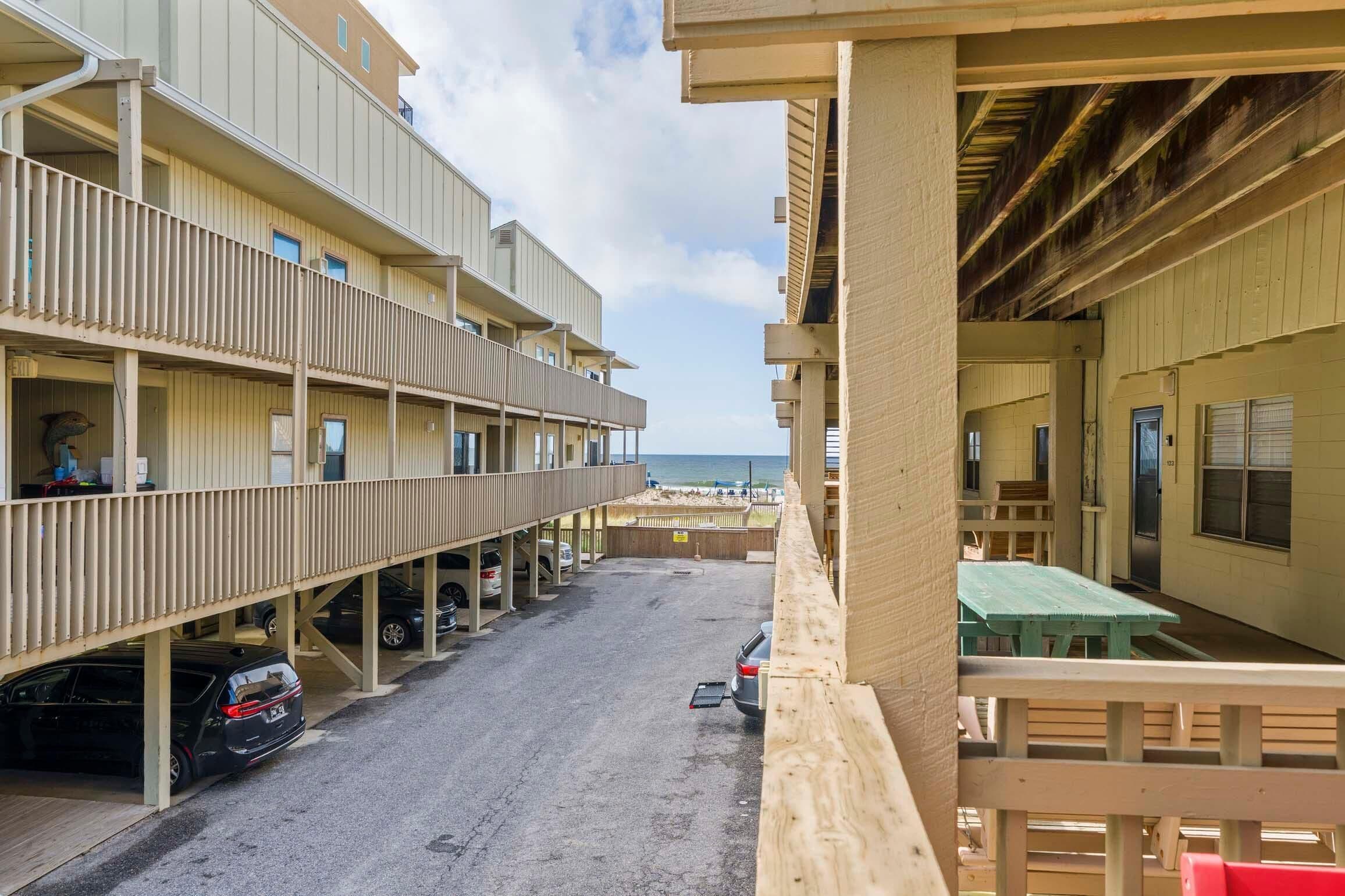 Et hotel med flere etager, altaner, parkeringsplads og udsigt til stranden.