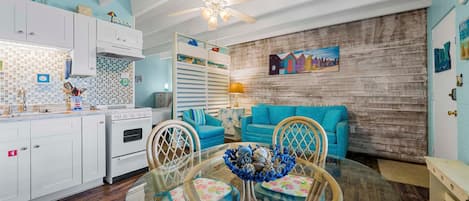 A kitchen with white cabinets, a stove, and a dining area with a glass table and chairs.