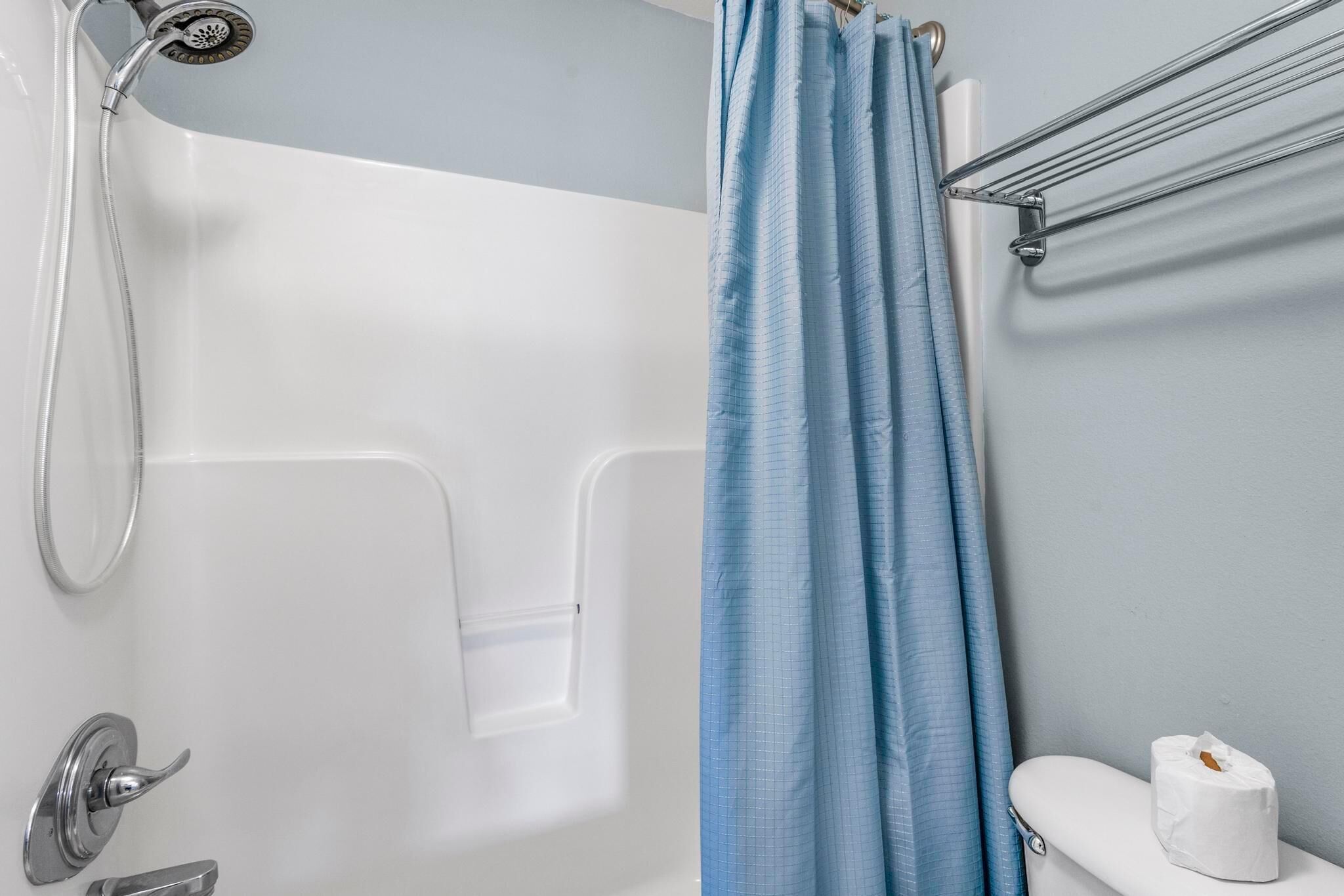A bathroom with a bathtub, a shower, a toilet, and a towel rack.