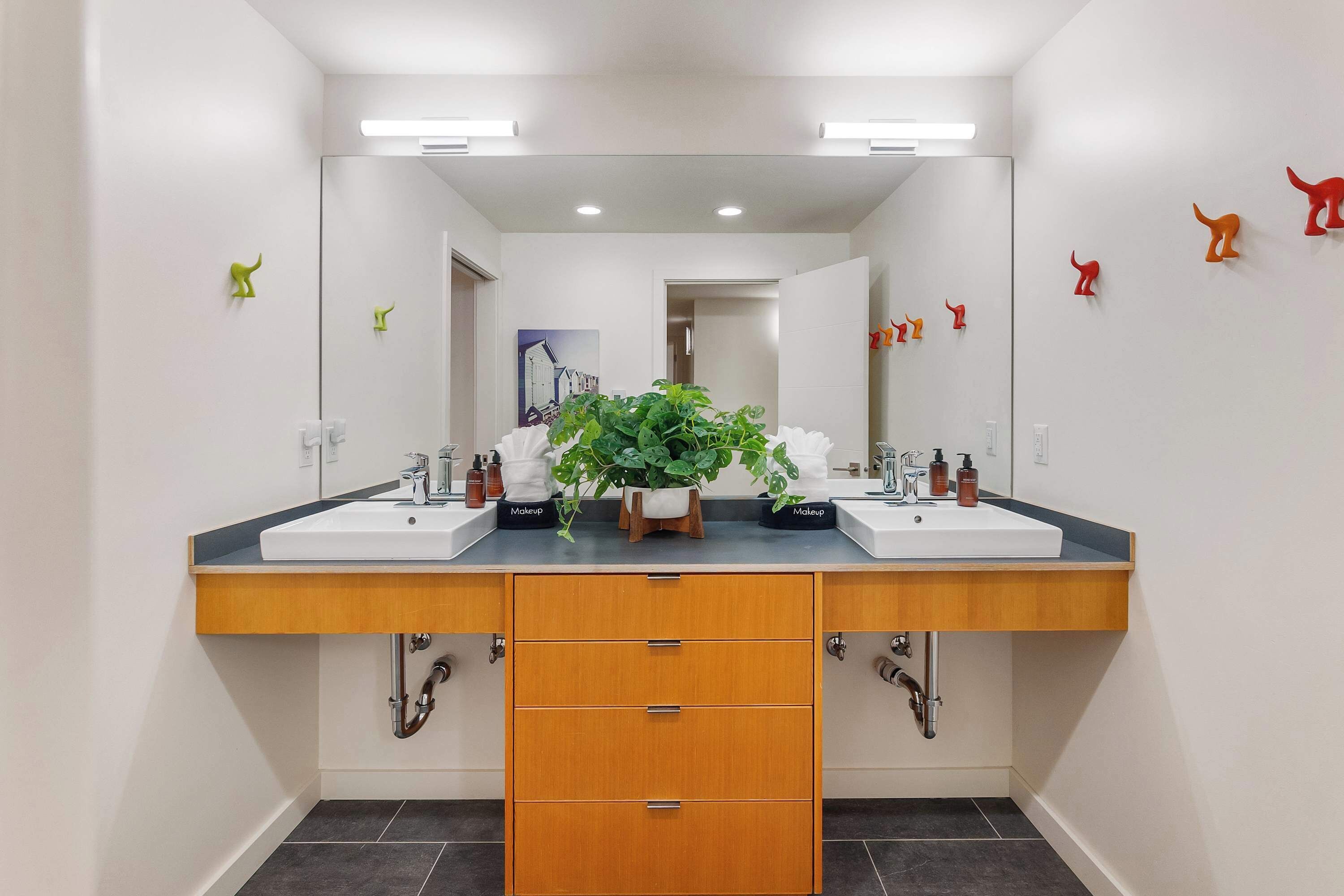 Een moderne badkamer met twee wasbakken, een spiegel en een houten kast met lades.