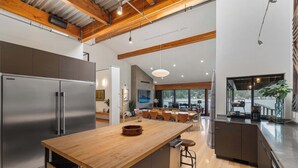 Una cucina moderna con una grande isola, elettrodomestici in acciaio inossidabile e travi in legno al soffitto.