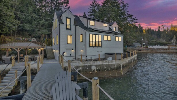 A waterfront house with a dock, a covered area, and a staircase leading to the upper levels. - Waterfront Retreat - Hot Tub, Fireplace, Pier (hoodsport)